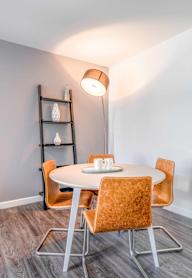 a dining area with a round table and orange chairs