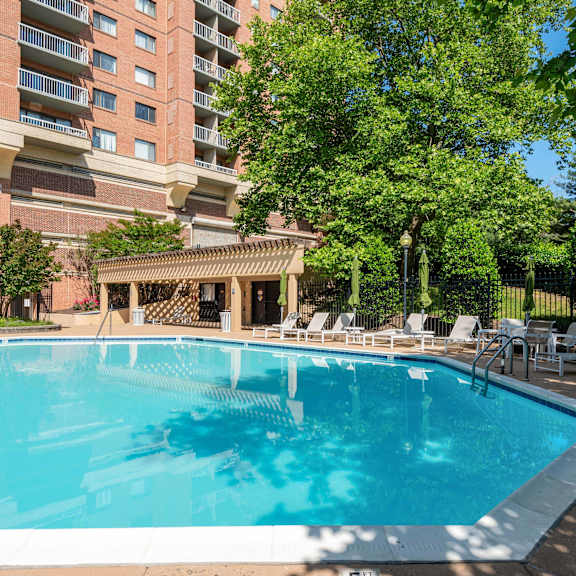 A large swimming pool surrounded by lounge chairs and trees.