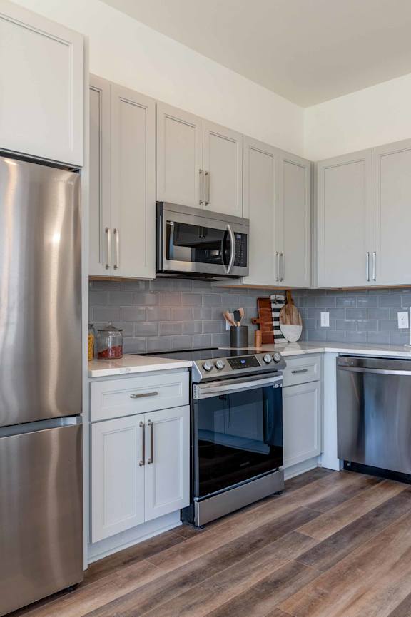 A kitchen with a stainless steel refrigerator and white cabinets.