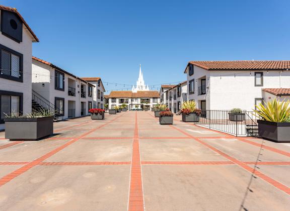 an empty parking lot with buildings and a church in the background