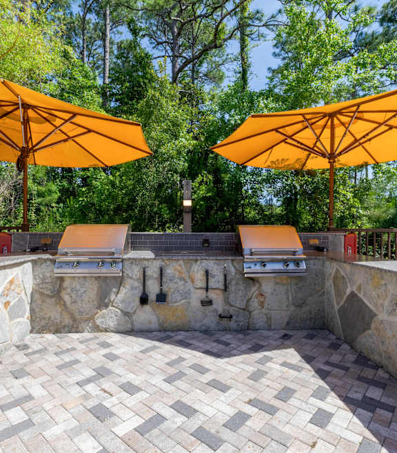 Two yellow umbrellas are over a stone patio.
