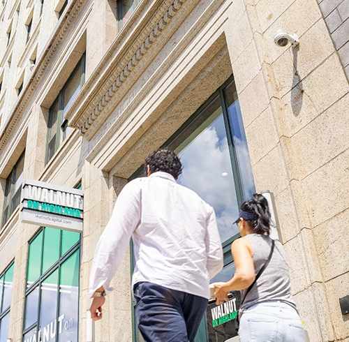 A man and a woman are walking together in front of a building. at Walnut on Highland, Pittsburgh, PA