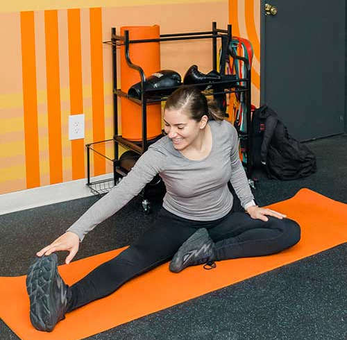 A woman stretches on an orange mat in a room at Walnut Towers at Frick Park, Pittsburgh, PA 15217