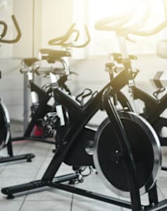 A row of stationary bikes are lined up in a gym.