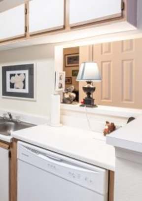 A kitchen with white cabinets and a grey curtain.