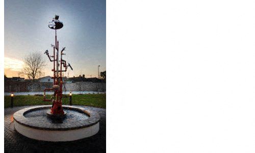 a water fountain in a park at sunset
