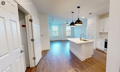 A kitchen with white cabinets and a wooden floor.