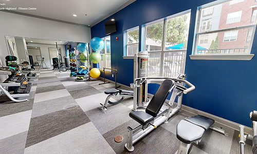 A gym with a variety of equipment including a treadmill, weights, and a bench press.