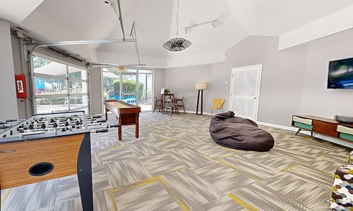 A room with a grey carpet and a brown bean bag chair.