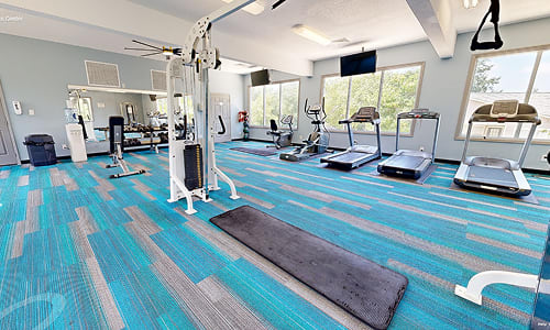 A gym with a variety of equipment including treadmills, weights, and exercise machines.