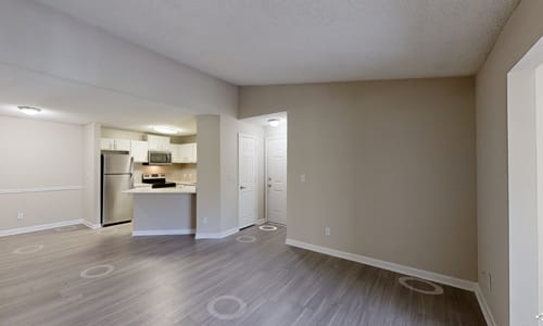 A kitchen with a refrigerator, sink, and oven is visible through a doorway.