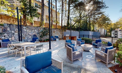 A patio with a stone wall and furniture.