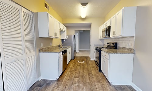 A kitchen with white cabinets and a black refrigerator.