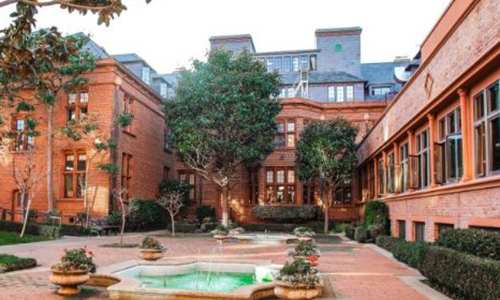 A large brick building with a pool in the front yard.