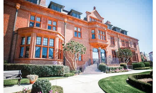A red brick building with a green lawn in front.