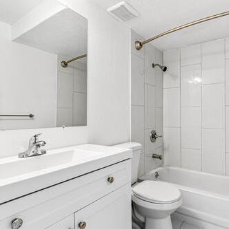 A white bathroom with a toilet, sink, and bathtub.