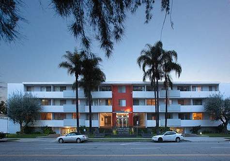 A red and white building with palm trees in front.