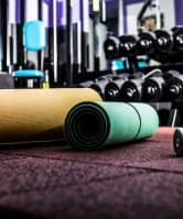 Rolled up yoga mats and dumbells on a gym floor