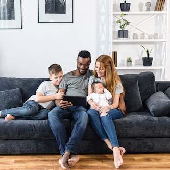 Family sitting on a couch looking at a tablet