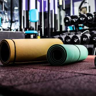 Rolled up yoga mats and dumbells on a gym floor
