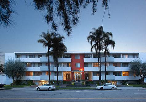 A red and white building with palm trees in front.