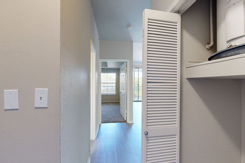 A hallway with a white door and a light switch on the wall.