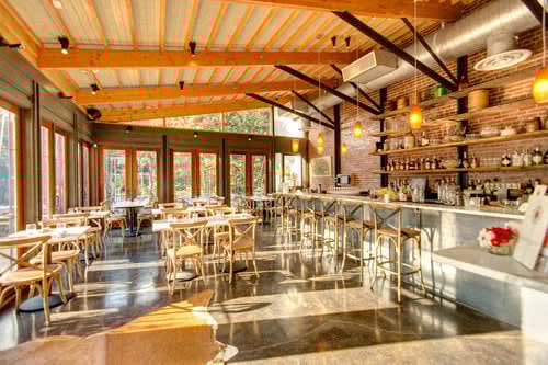 the interior of a restaurant with tables and a bar