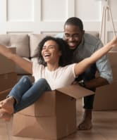 a couple sitting in a cardboard box with their arms outstretched