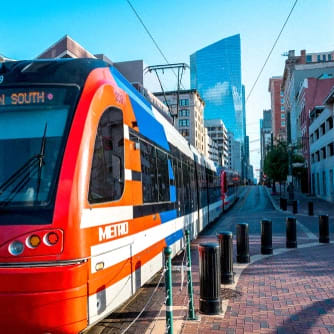a red and orange train on the street in a city