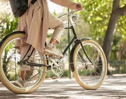 A person in a beige coat is riding a bicycle.