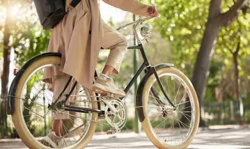 A person in a beige coat is riding a bicycle.