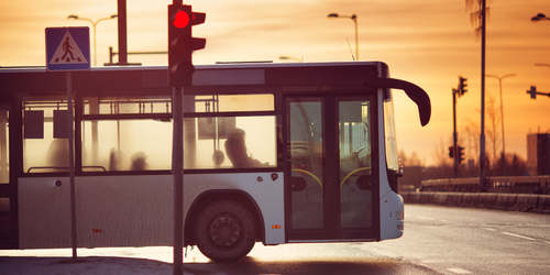 a bus stopped at a traffic light with the sun setting in the background
