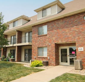 a brick apartment building with a tree in the yard