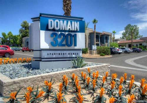 A sign for Domain 3201 Apartment Homes is displayed in front of a building.