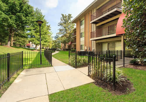 A black metal fence surrounds a grassy area in front of a building.