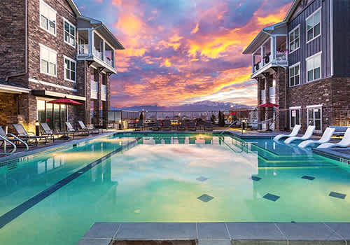 a swimming pool with chairs and a sunset in the background