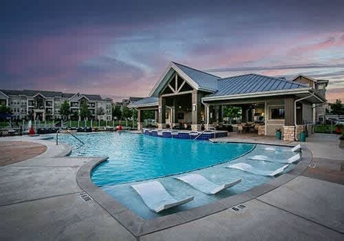 a swimming pool in the evening at a resort with large buildings