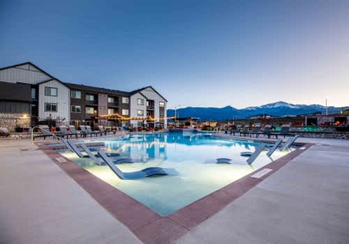 A large outdoor swimming pool with a slide and loungers is lit up at dusk.