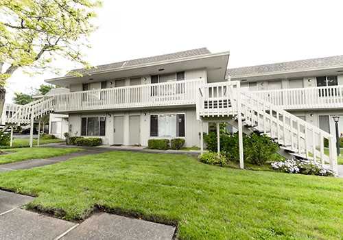 A white building with a balcony and stairs leading to it.at OTAVON APARTMENTS, Novato, CA 94947