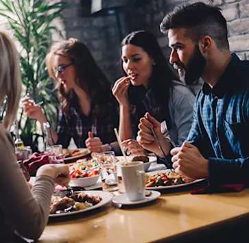 a group of people sitting around a table eating food at a restaurant