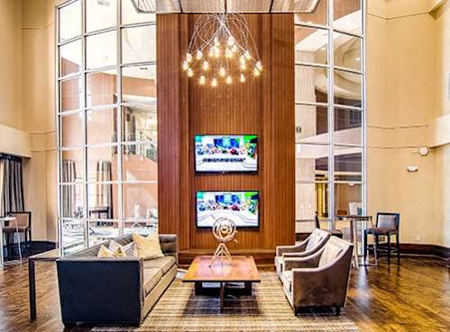 A large room with a TV on the wall and a long wooden column.