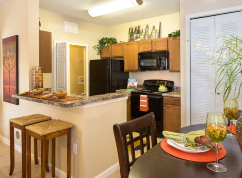 a kitchen with a table and chairs next to a counter top with a glass of wine on