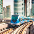 A blue and white train is on tracks in a city.