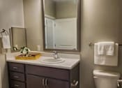 Thumbnail 6 of 17 - A bathroom with a white toilet and a sink with a mirror above it.