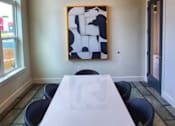 Thumbnail 10 of 17 - A white table with a white cloth on it and a painting on the wall behind it.