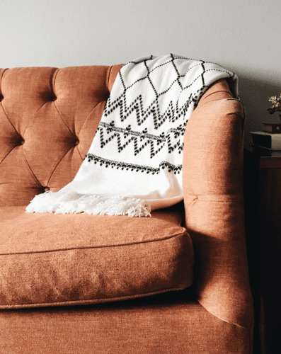 A brown chair with a white and black patterned throw blanket draped over it.