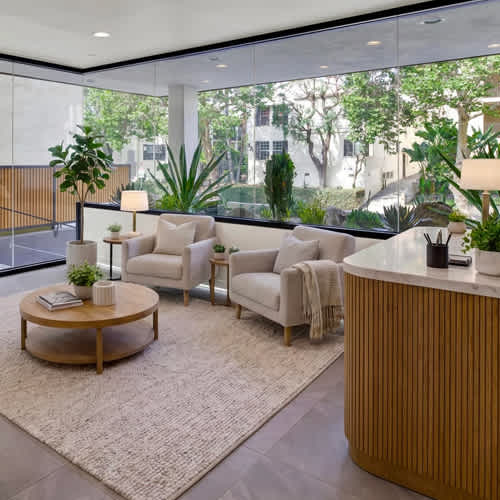 A modern living room with a large window and a view of trees and buildings outside.