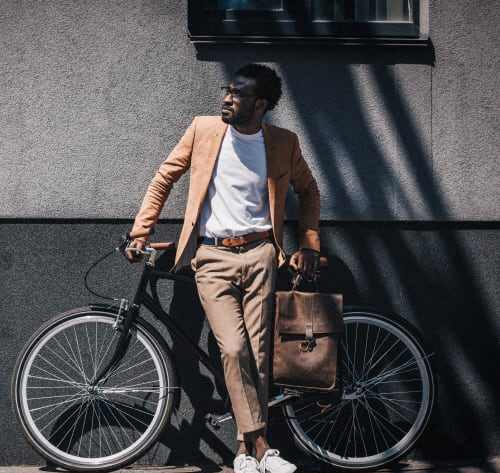 A man in a tan suit stands next to a bicycle holding a brown bag.at 21 West, New York, NY 10006
