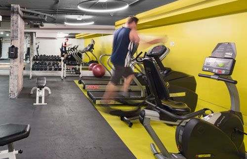 fitness room with exercise equipment and a person running on a treadmill