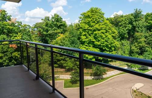 Large balcony overlooking trees and parking area.